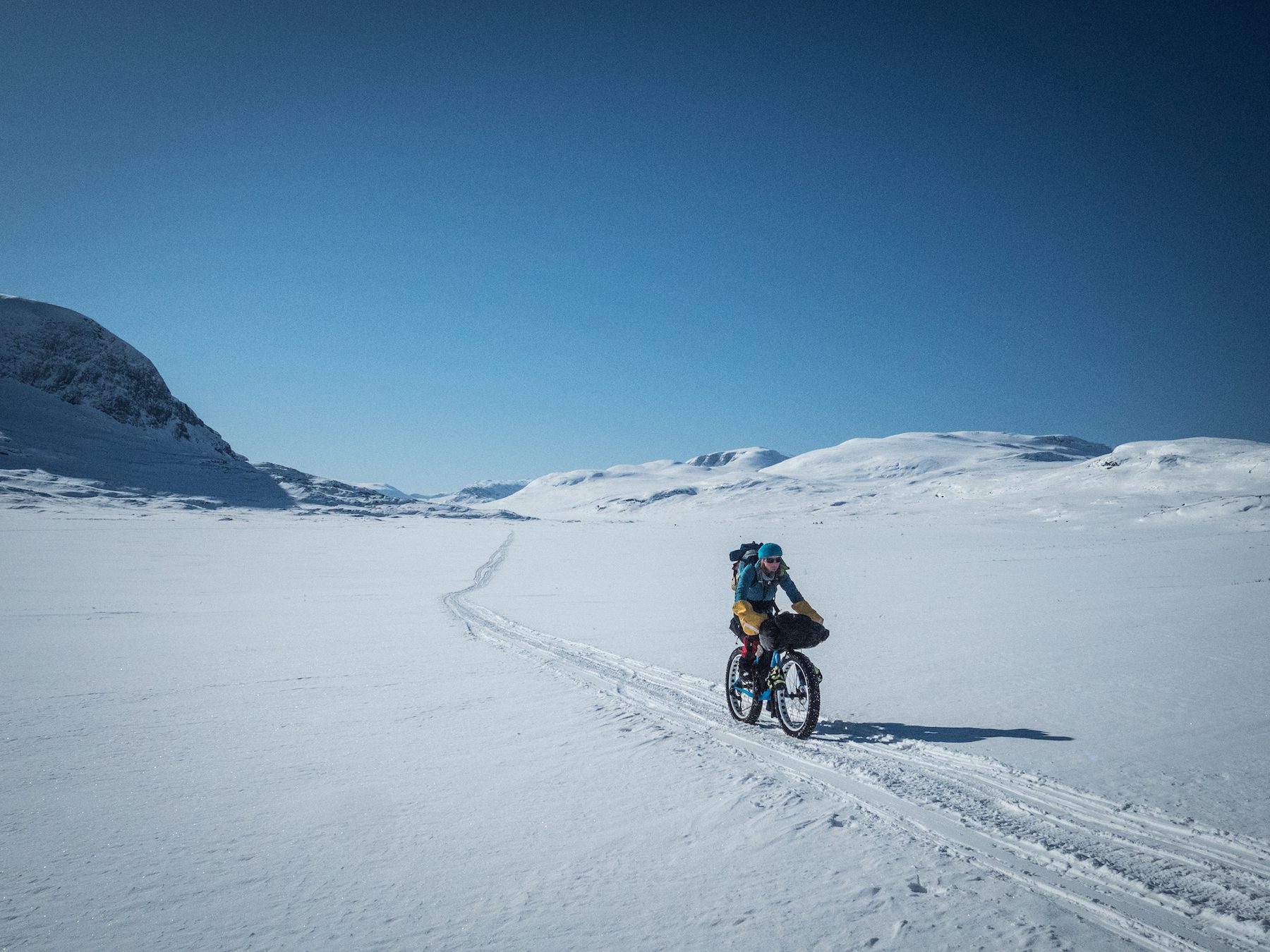 "Space. Snow covered landscapes, with reduced texture and the lakes becoming rideable surfaces, seem so vast. The snowmobile tracks were the only lines for miles, enticing us to go ever onwards. We found it took several slow moving snowmobiles through the soft snow to create a packed enough trail to ride easily. The busy open ski tracks were often much faster going, although falling off them resulted into being buried in deep powder." ~Annie Le Evans