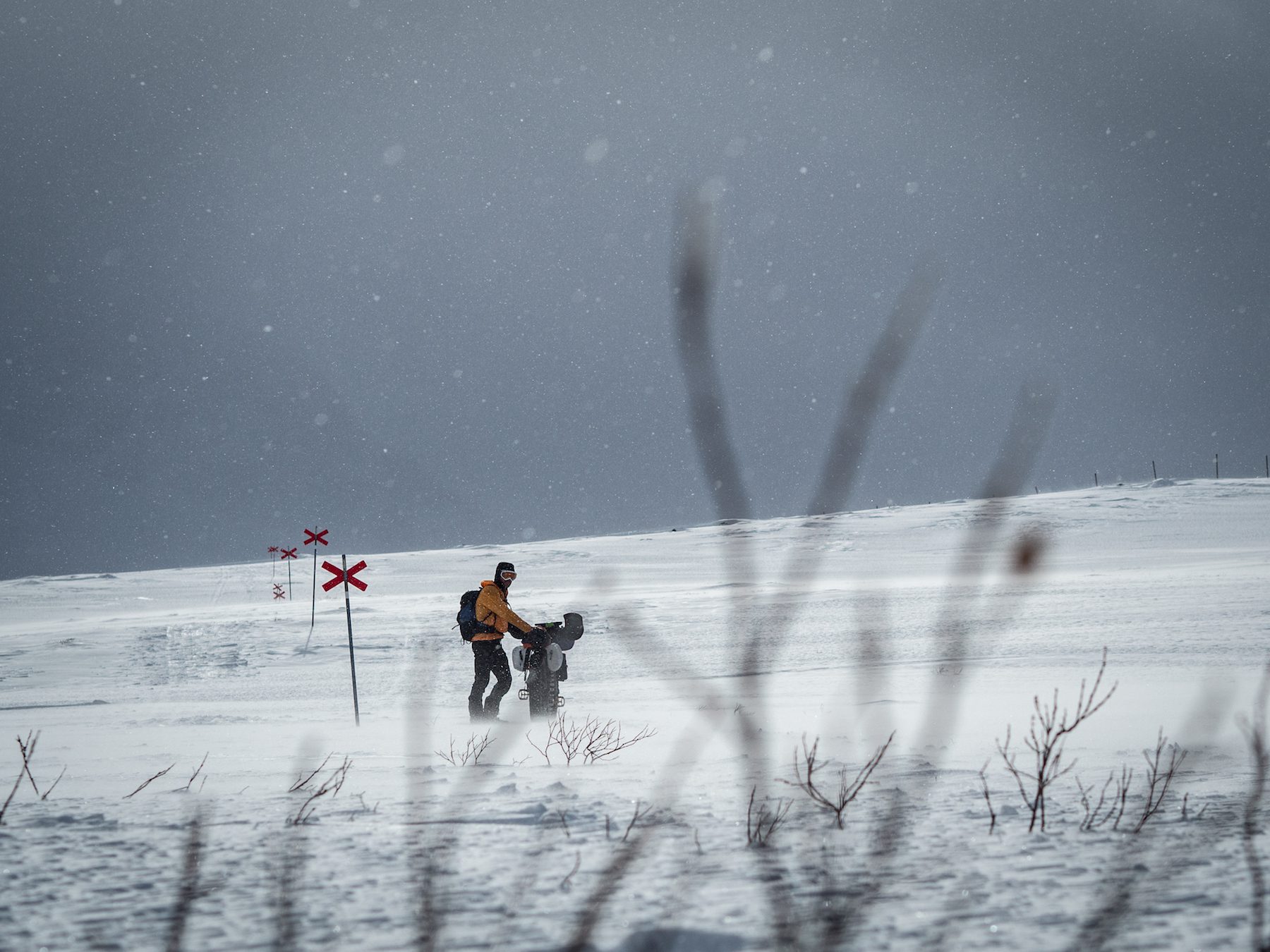 "As our route took us up and over the mountain plateau to the south of Abisko, the weather turned against us. Warmer temperatures, wind, and persistent snow made hard going as the trail drifted over, and the risk of getting wet increased. The red markers that line the routes of ski trails throughout Scandinavia were a comforting sight as they marched across the plateau, but they also beckoned towards a false sense of security. As the snow deepened, we pushed into the early evening, before deciding to stop beside Alesjaure and see what the morning held for us." ~Huw Oliver