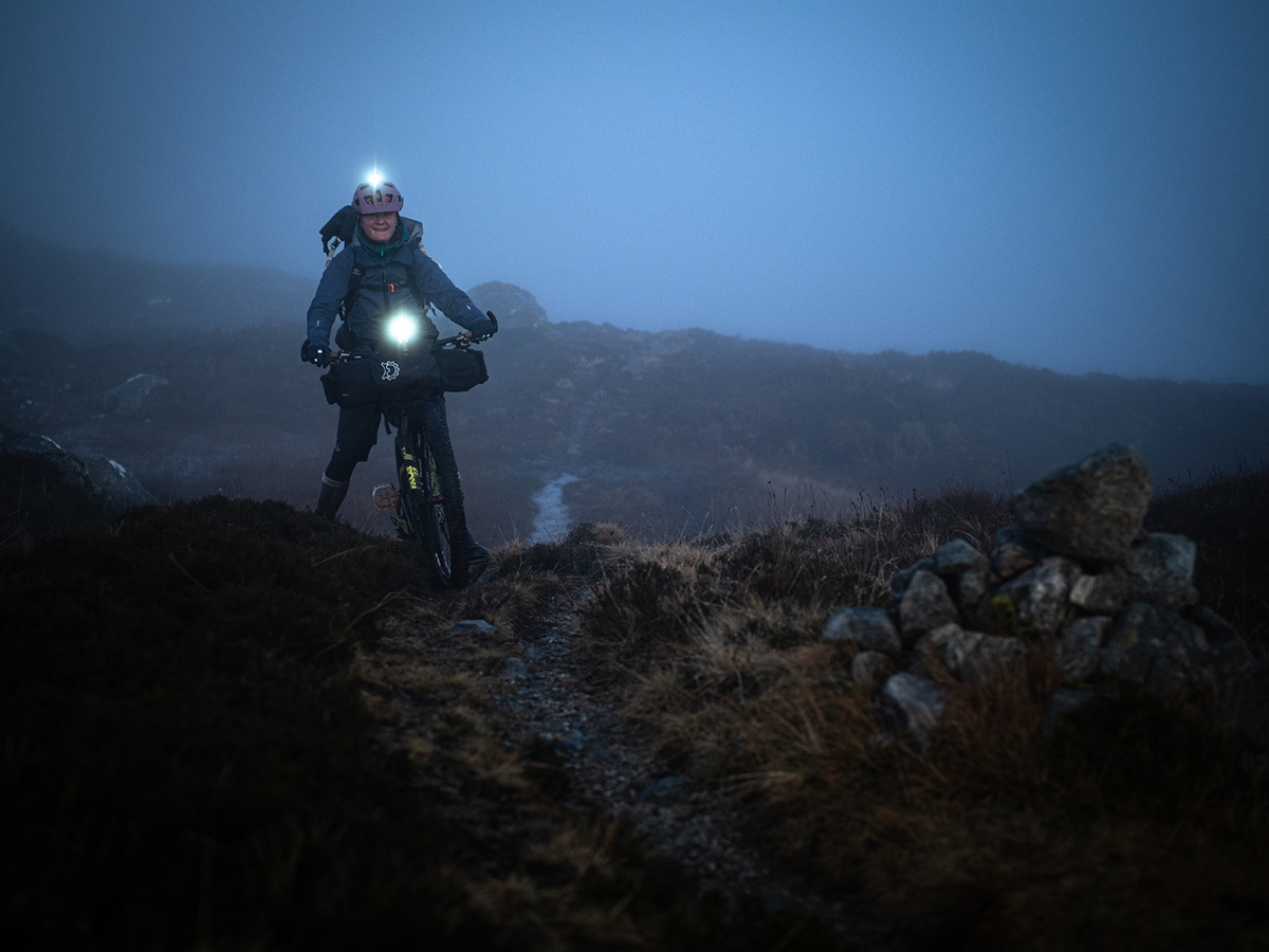 Annie bikes at night through fog with headlamps